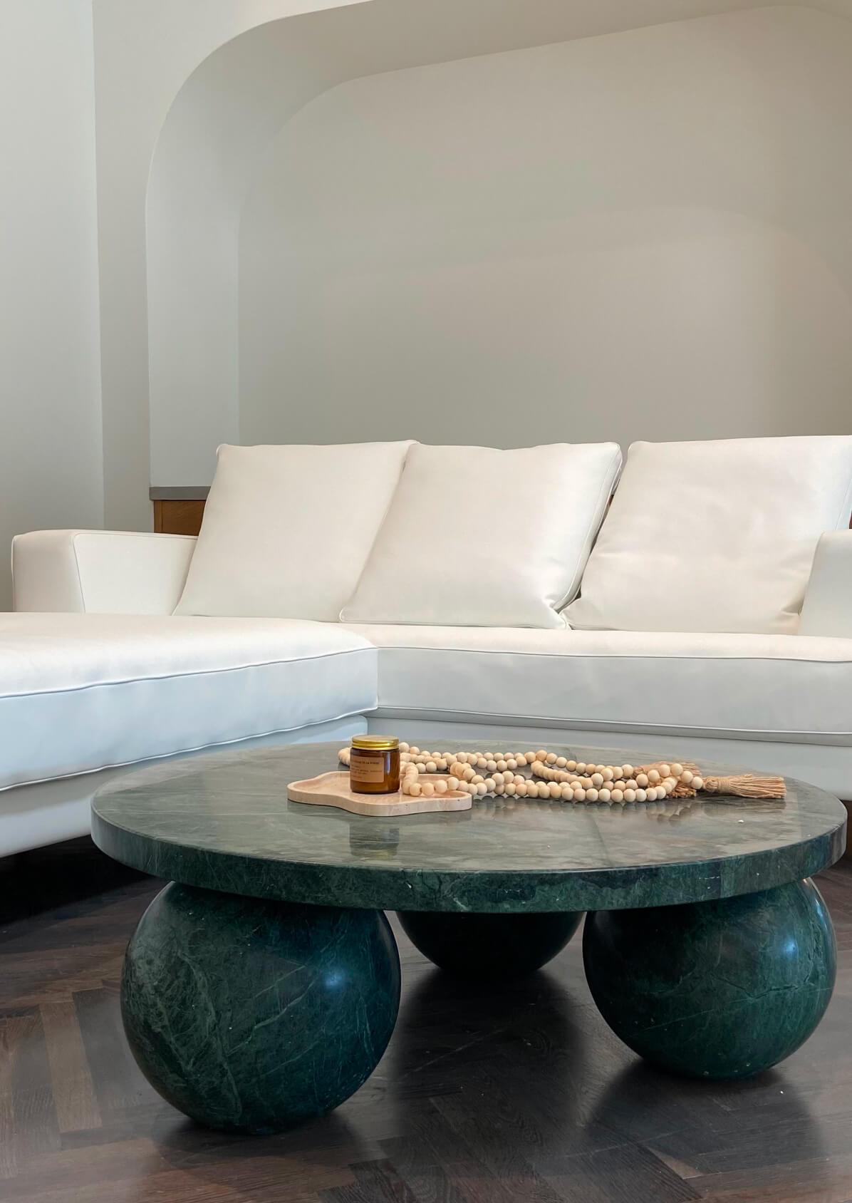 Modern living room with a white sectional sofa and a round green marble coffee table
