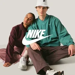 Twee jonge volwassenen zitten op de vloer, een steunt haar hoofd op de schouder van de ander, beiden dragen casual sportieve kleding en sneakers.