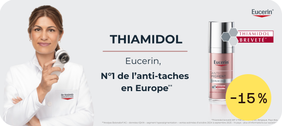 Une femme en blouse blanche tient un applicateur près de son visage sur fond gris. À gauche figure le logo Eucerin. Au centre, le texte « THIAMIDOL » puis « Eucerin, N°1 de l’anti-taches en Europe** ». À droite, un flacon de soin avec la mention « THIAMIDOL BREVETÉ ».
