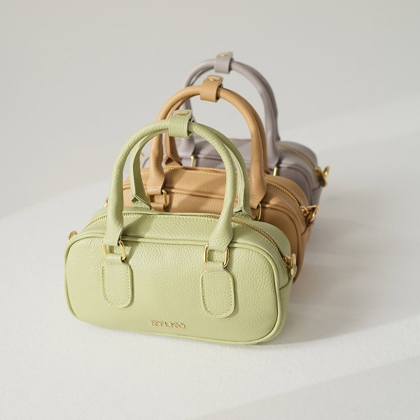 Three stylish handbags in pastel colours, arranged in a row on a light surface.