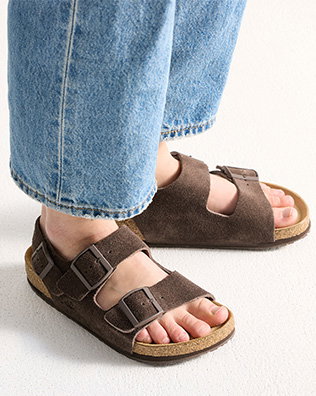 Person som bär bruna mockasandaler med spänne bak