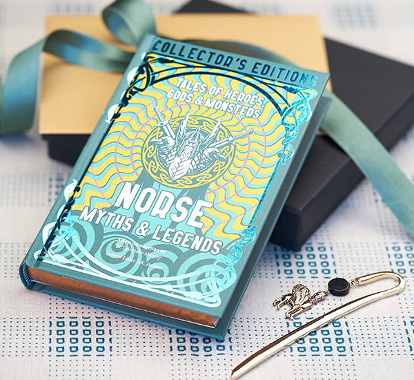 Norse Myths and Legends hardback book on a gift box with ribbon next to a metal Assyrian winged bull bookmark. - Shop Mythology Books.