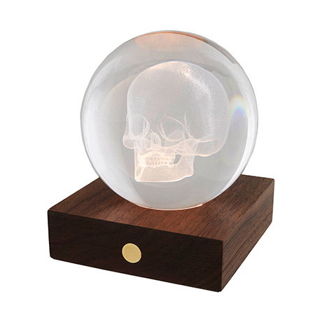 Glowing amber crystal ball ornament showcasing a detailed three-dimensional skull design. - Shop Now.
