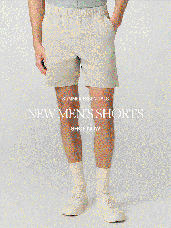 Man wearing a pair of cotton elastic waistband shorts in a light neutral shade, posed in front of a light grey backdrop. Summer Essentials: New Men's Shorts - Shop Now.