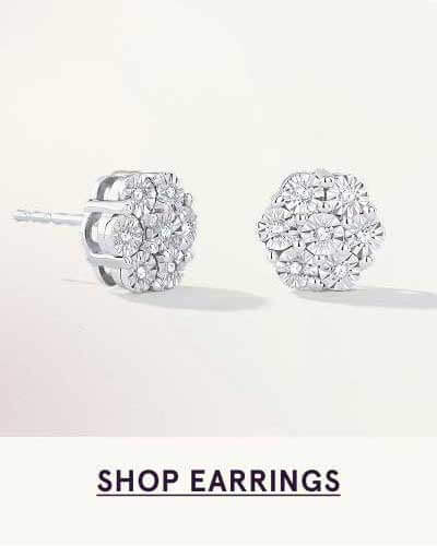 Pair of silver studs featuring floral cluster of round diamonds. Click here to shop earrings