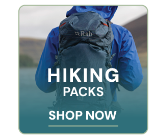 HIKING PACKS. A hiker walks along the trail wearing a Rab Protium 35L Day Pack in Blue. 