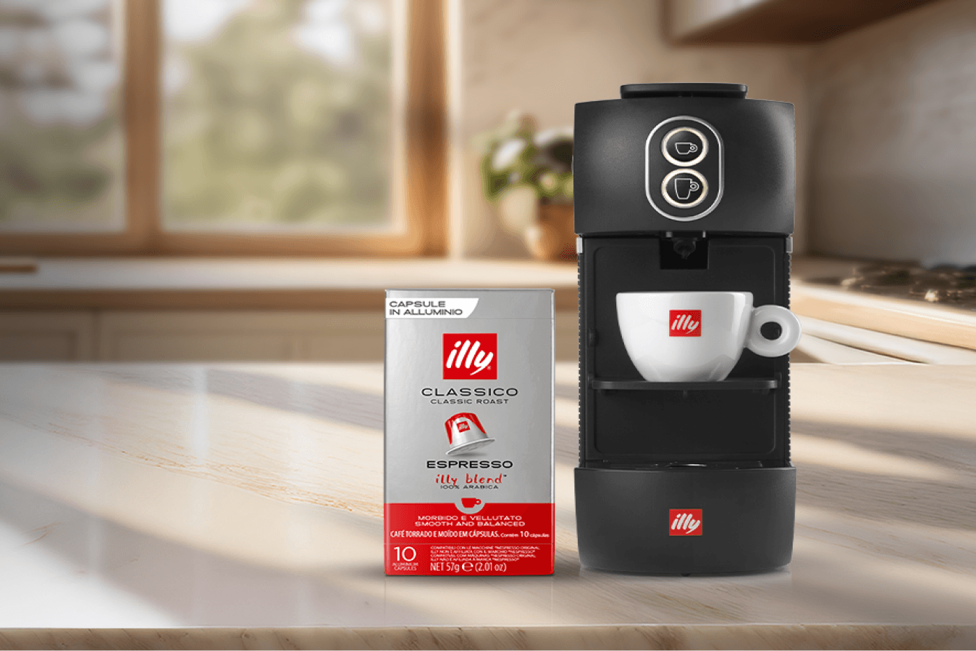 Black Illy espresso machine with coffee capsule box and espresso cup on a kitchen counter