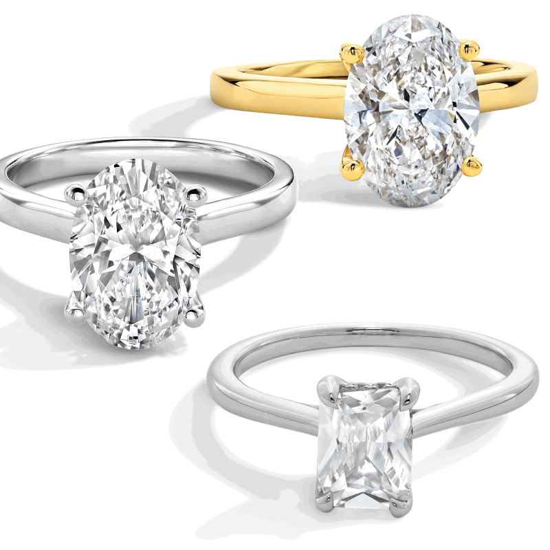 Three diamond engagement rings with oval and emerald-cut stones in yellow and white gold solitaire settings.