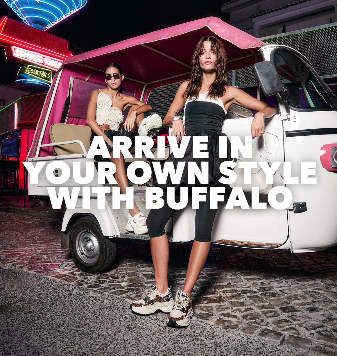 Promotional image showing two people posing beside a small vehicle at night, wearing chunky Buffalo sneakers, with neon lights and the text ‘Arrive in Your Own Style with Buffalo’.”