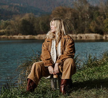 A woman sitting in a field holding a water bottle