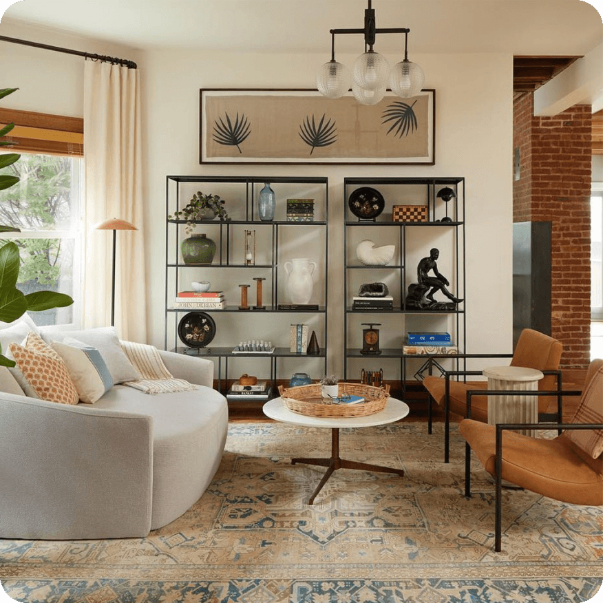 Two black metal Foshay bookcases styled with decor behind a sofa and chairs in a living room.