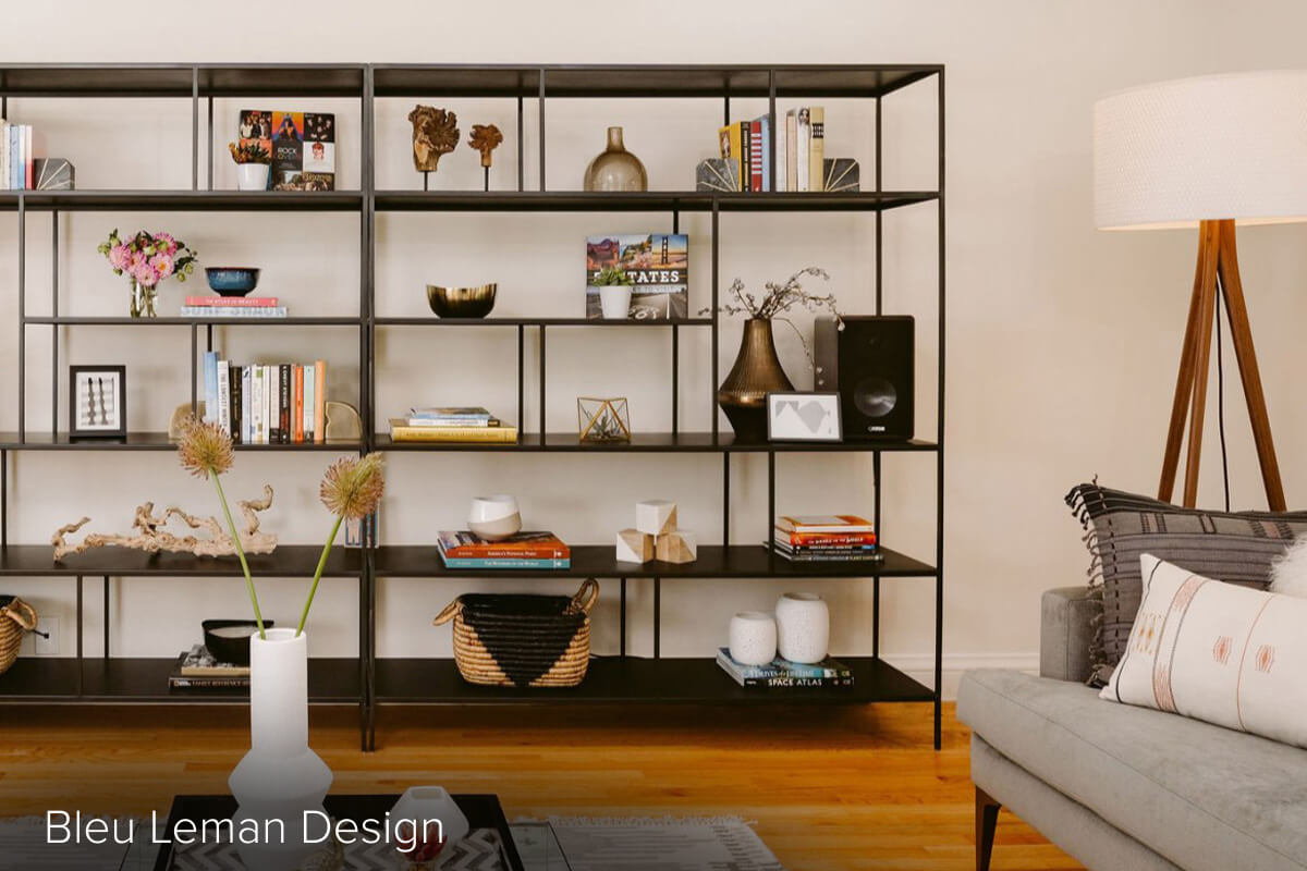 Black Foshay bookcases with books, baskets and decor displayed behind a sofa and floor lamp.