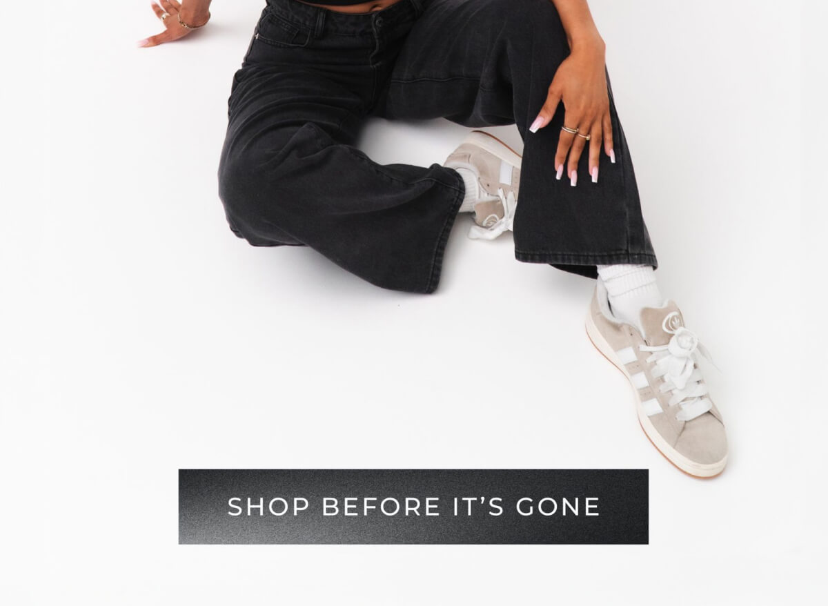 Woman in black jeans and white sneakers sitting on white background with 'Shop Before It's Gone' button
