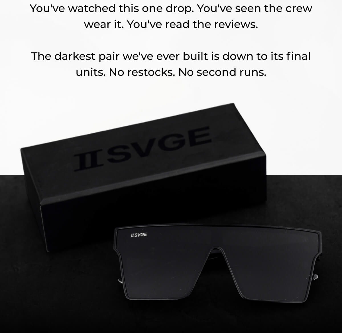 Black Two Svge sunglasses with dark lenses next to branded black box packaging on dark surface