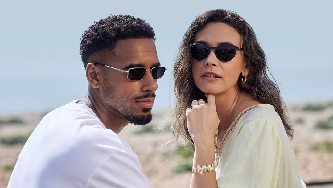Man in rectangular sunglasses and woman in round sunglasses, outdoors