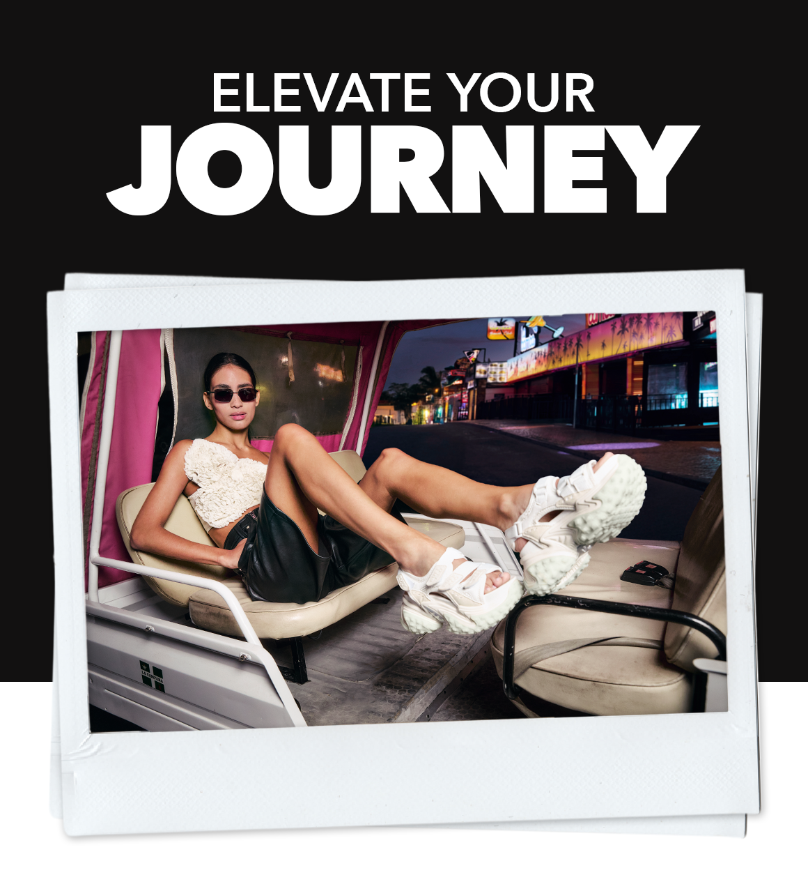 Promotional image showing a person reclining inside a vehicle at night, wearing chunky white sandals, with the text ‘Elevate Your Journey’.