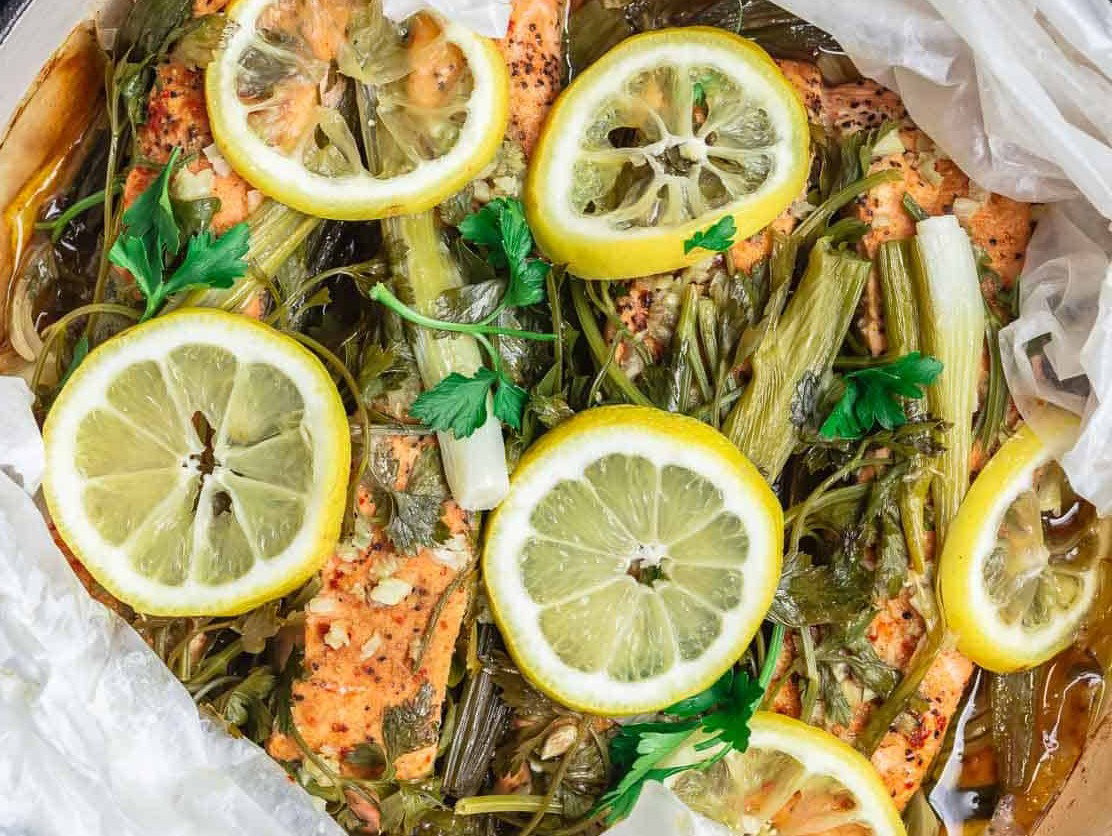 Steamed salmon in parchment in a skillet.