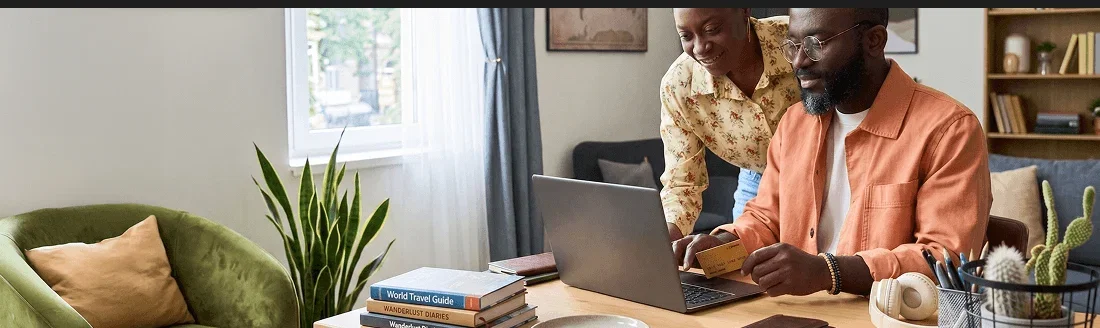 A couple researching travel documents on a laptop at home.