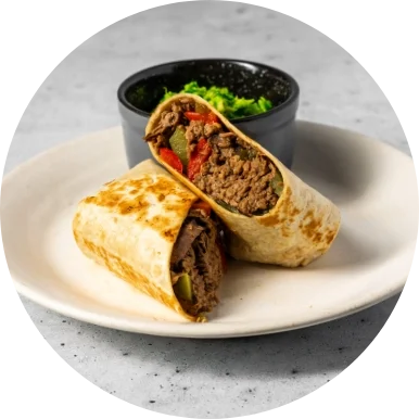 Burrito on a cream colored plate with a side of guacamole