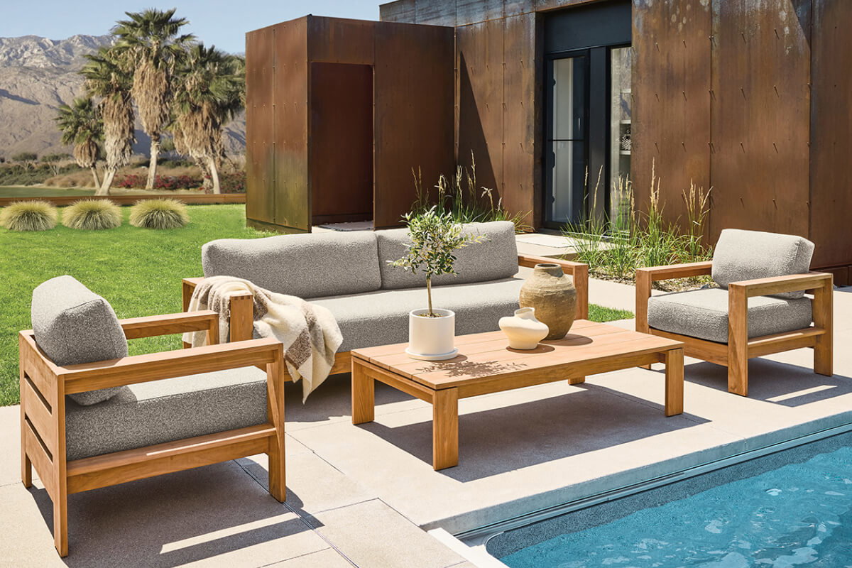 Leti seating set with teak frames and grey cushions around a coffee table on a poolside patio.