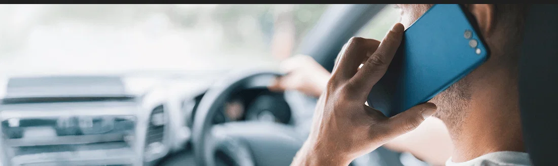 A driver using a mobile phone at the wheel of a car.