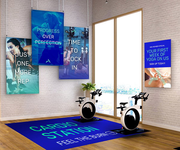 A fitness studio featuring three banners, a poster, and a floor graphic.