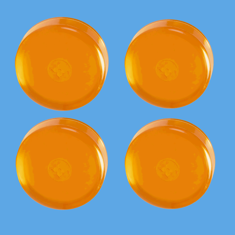 Four orange-colored round soap bars with a flower-like imprint in the center, arranged in a 2x2 grid against a bright blue background. (square)