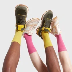 Dos pares de zapatillas: una en verde oliva con acentos en amarillo, y la otra en beige con malla blanca. Medias de color amarillo brillante y rosa visibles.
