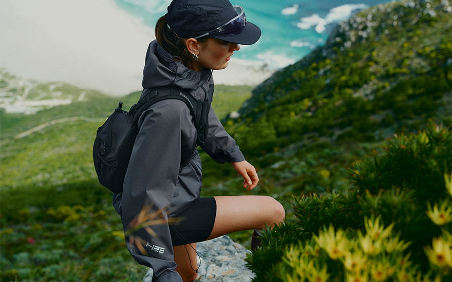 A woman hiking through a lush green landscape, wearing outdoor hiking clothing.
