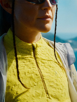 Close-up of a woman wearing a yellow midlayer top, with the garment in sharp focus.