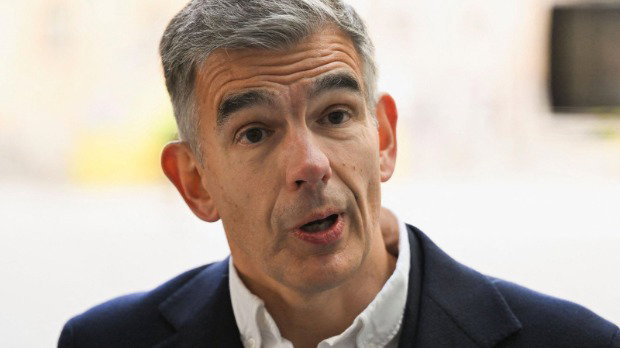 A close-up of Matt Brittin on arrival at BBC HQ in London, wearing a white shirt and a dark suit jacket. He has short grey-black hair and the background is blurred.