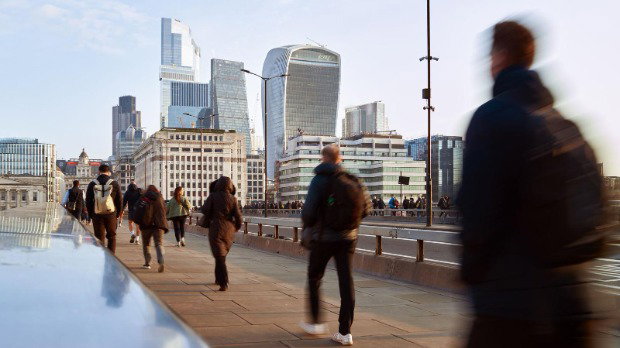 People commuting to work over a bridge in London on a bright day.