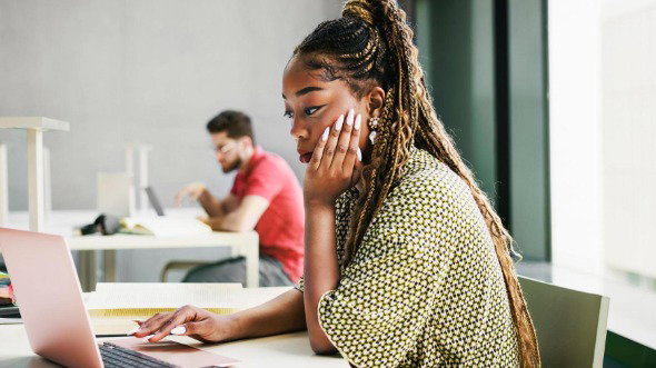 A young woman works from a laptop in a modern office.