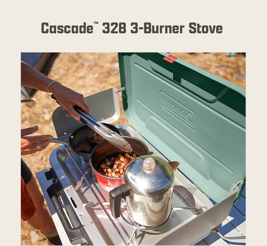 Cascade 328 3-Burner Stove text at top. Person cooking food on a green stove outdoors using tongs and pans.
