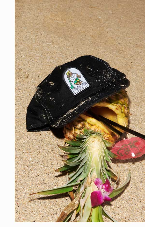K-Man Hat sitting on a pineapple drink at the beach