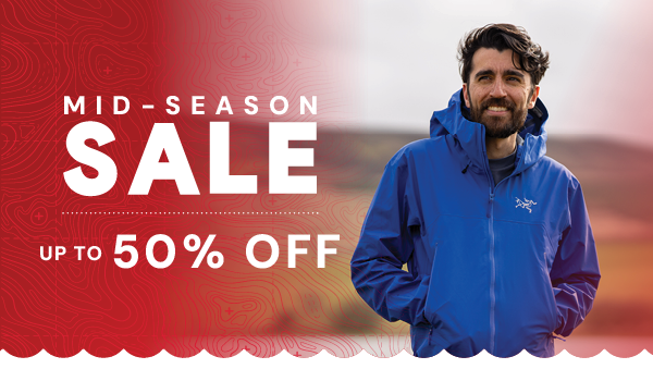 SALE: UP TO 50% OFF. A man walks through a valley wearing Arc'teryx Men's Beta SL Jacket in Vitality II. 