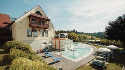Hotel Außenansicht mit Pool, Liegen und Sonnenschirmen