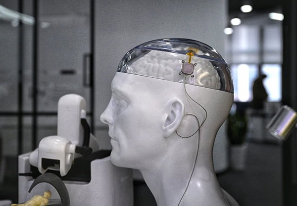 A mannequin head with a transparent section revealing the brain inside and a wired sensor attached.