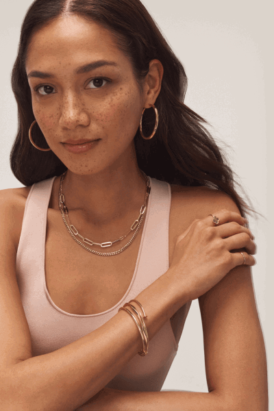 Woman wearing a variety of yellow gold fine jewelry.