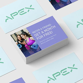 A stack of referral cards promoting a refer-a-friend program at a fitness studio.