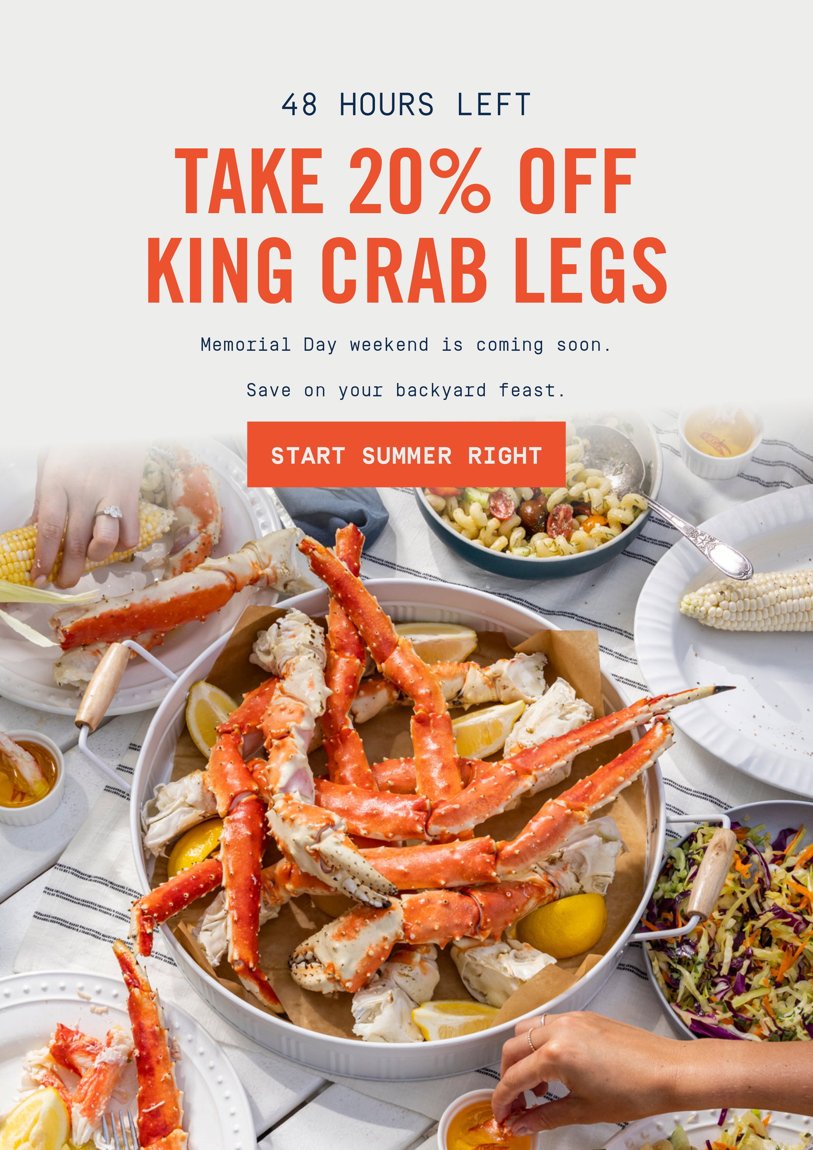 hands reaching into grab a king crab leg from platter of king crab legs with lemons.