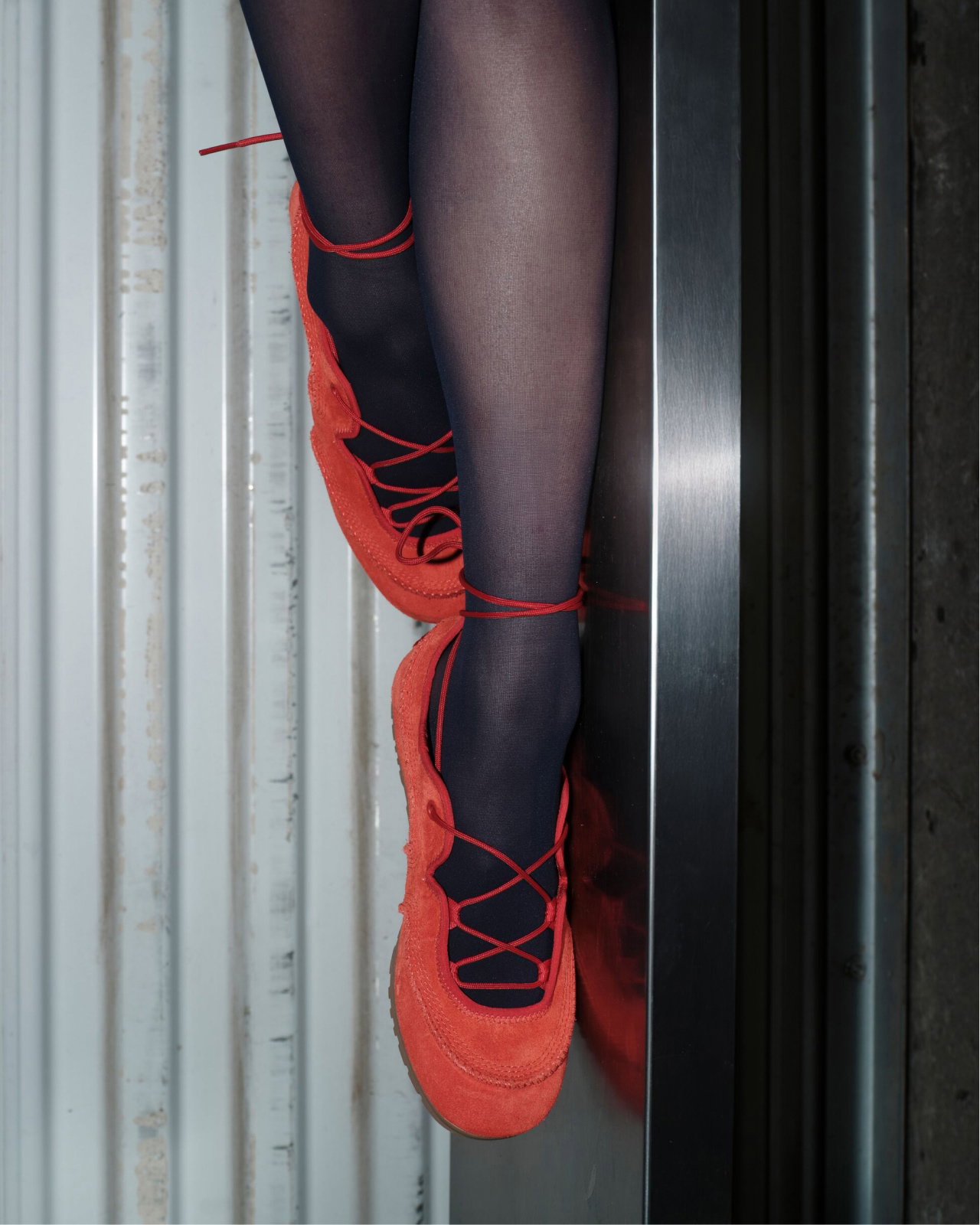 Legs wearing black tights and the quill ballerina trainer against a metallic background.