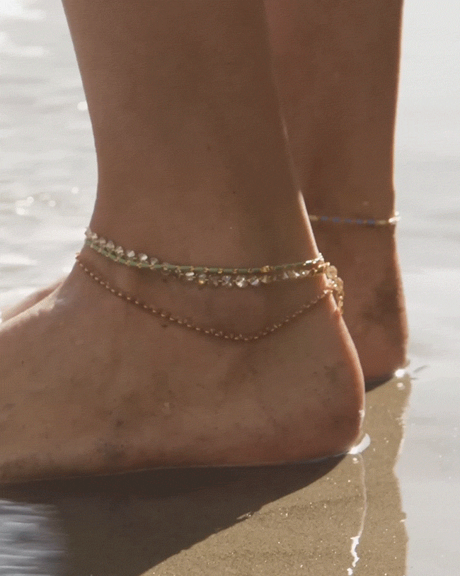 GIF of model wearing anklets in the water.