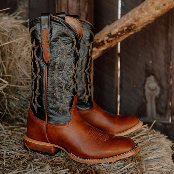 A pair of Tony Lama boots on a hay bail.