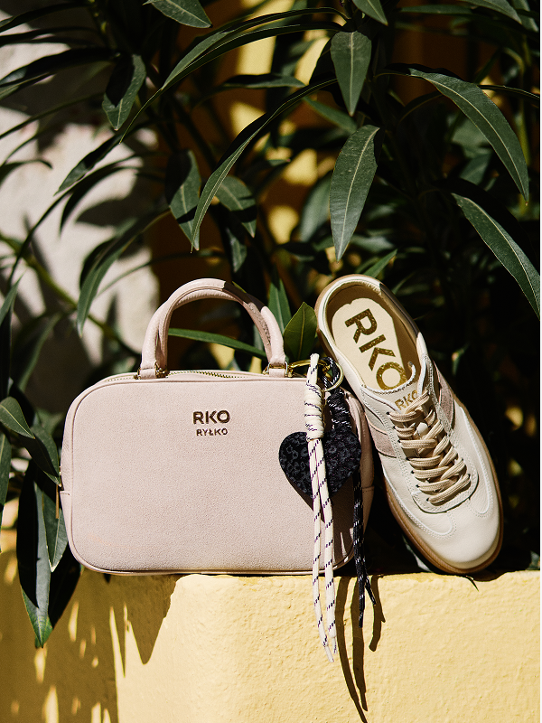 Beige RKO handbag and sneaker displayed outdoors with green leaves