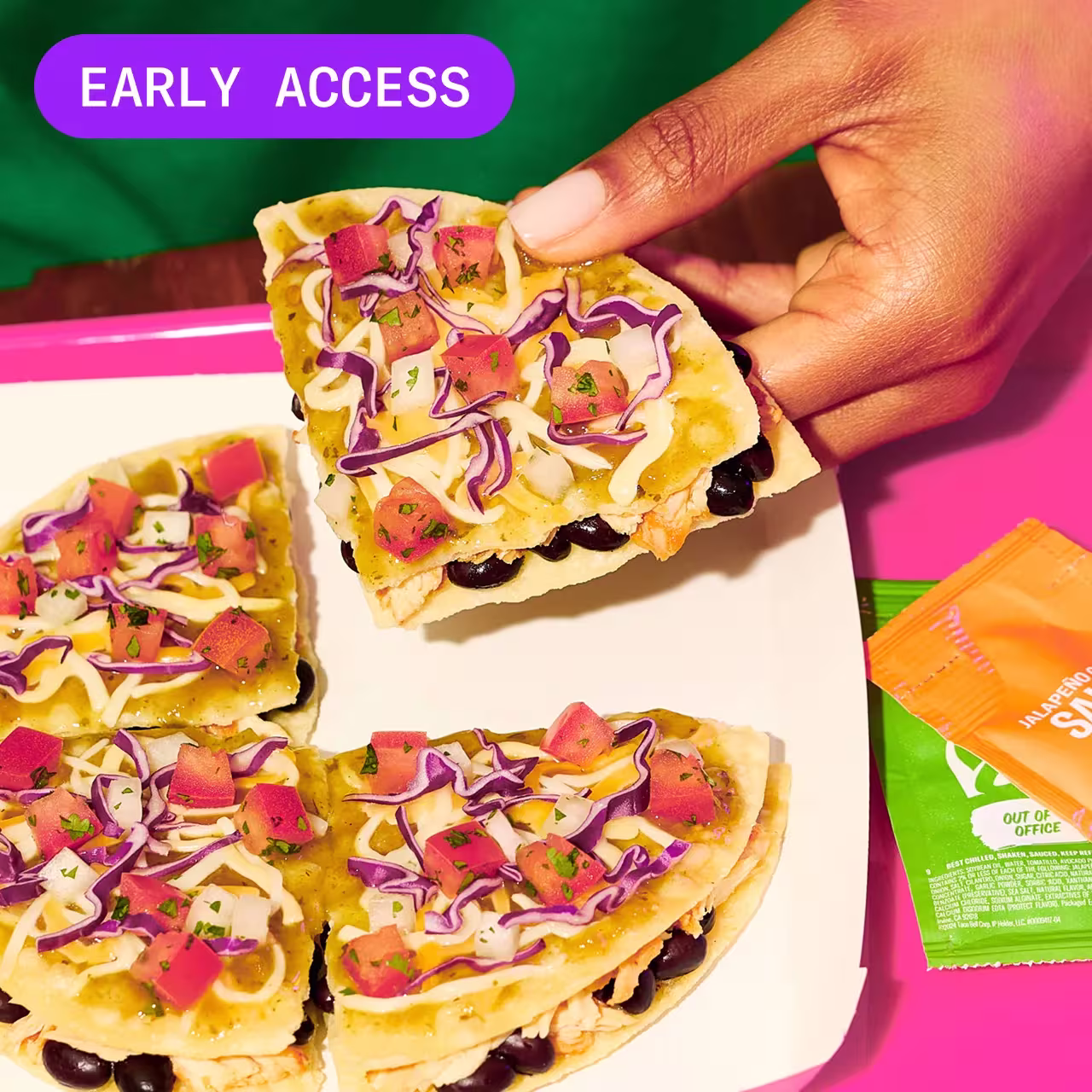 A hand holding a slice of Cantina Chicken Mexican Pizza with the other three slices on a plate.