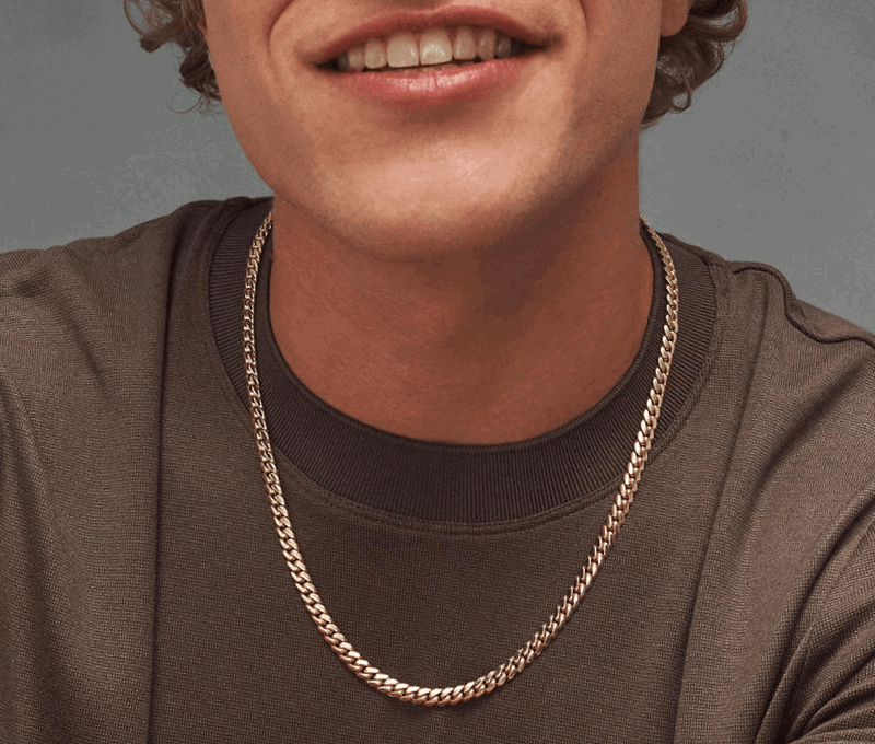 Man wearing brown shirt and gold chain link necklace.