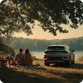 Couple sitting near lake next to car