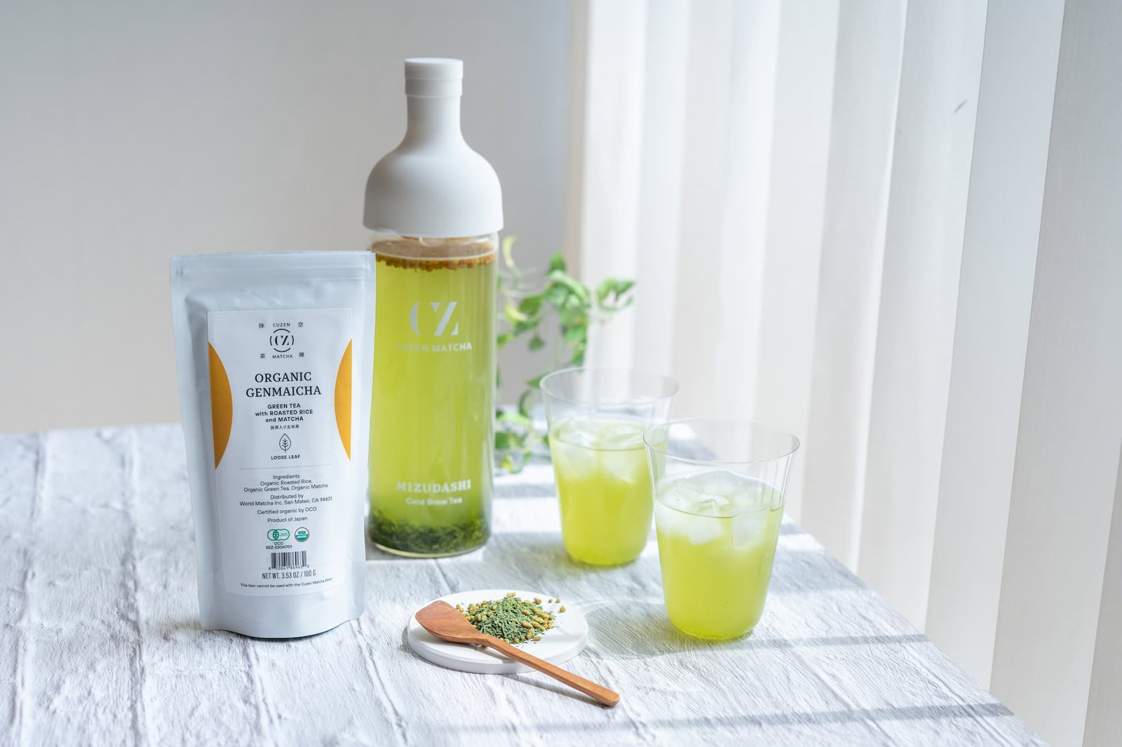 A 100 gram-packet of Cuzen Matcha Genmaicha Loose Leaf, a filter-in bottle and two glasses of cold brew tea.