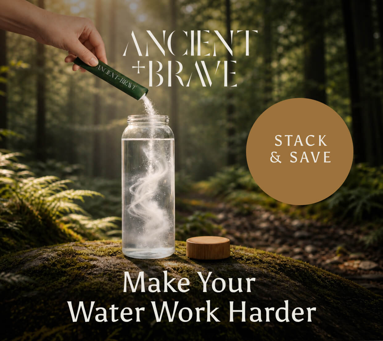 Ancient + Brave. A hand pours a sachet of powder into a glass water bottle on a mossy forest floor, with white wisps swirling through the water. Stack & Save. Make Your Water Work Harder.